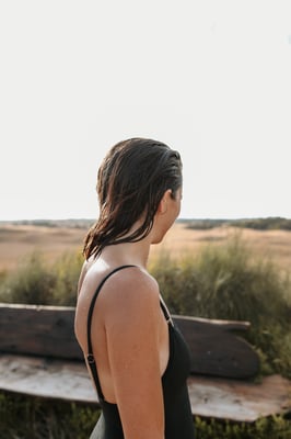 A woman in black bathers looking out to the view at the Hilltop pool
