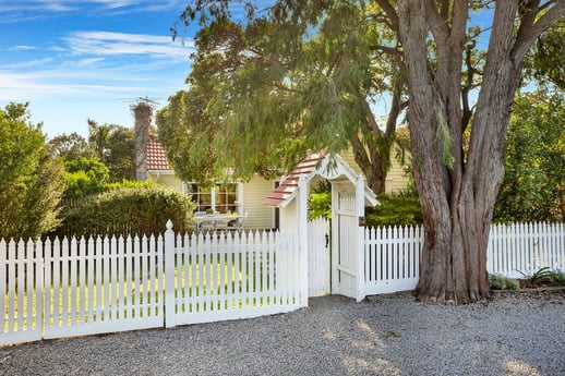 A cottage style house with a white picket fence