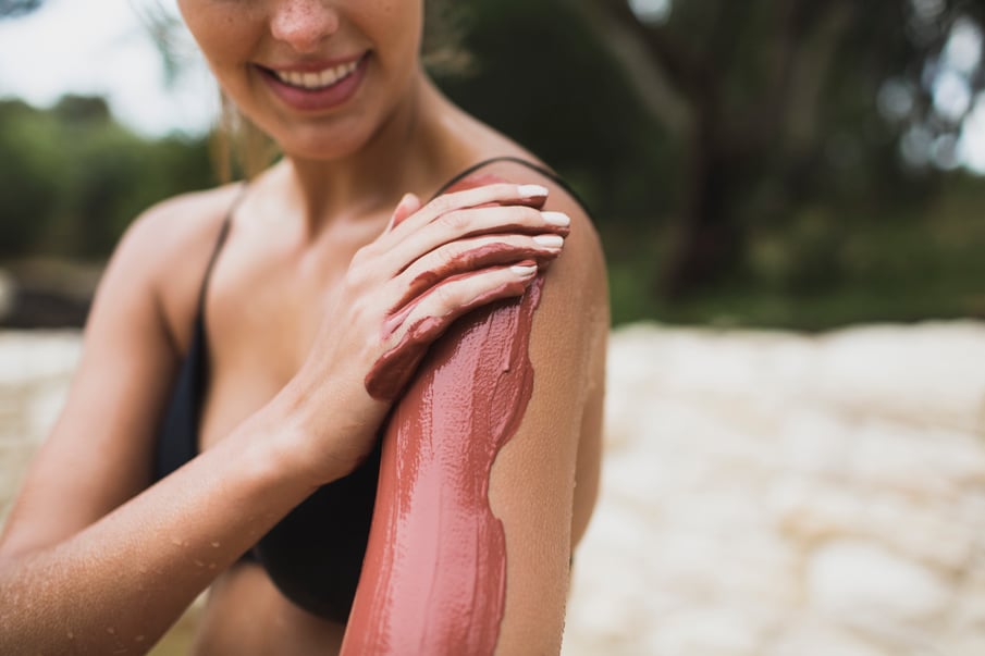 A person rubbing clay up their arm