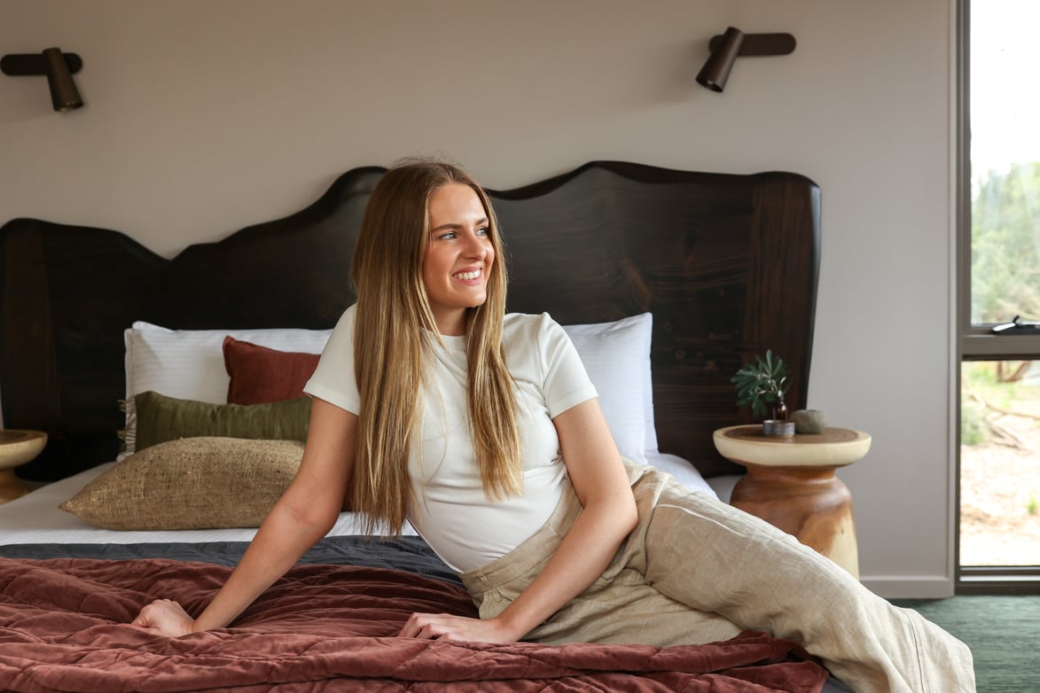 A young woman lazing on a king sized bed in the Eco Lodges