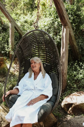 A woman sitting in an egg chair while wearing a plush white robe